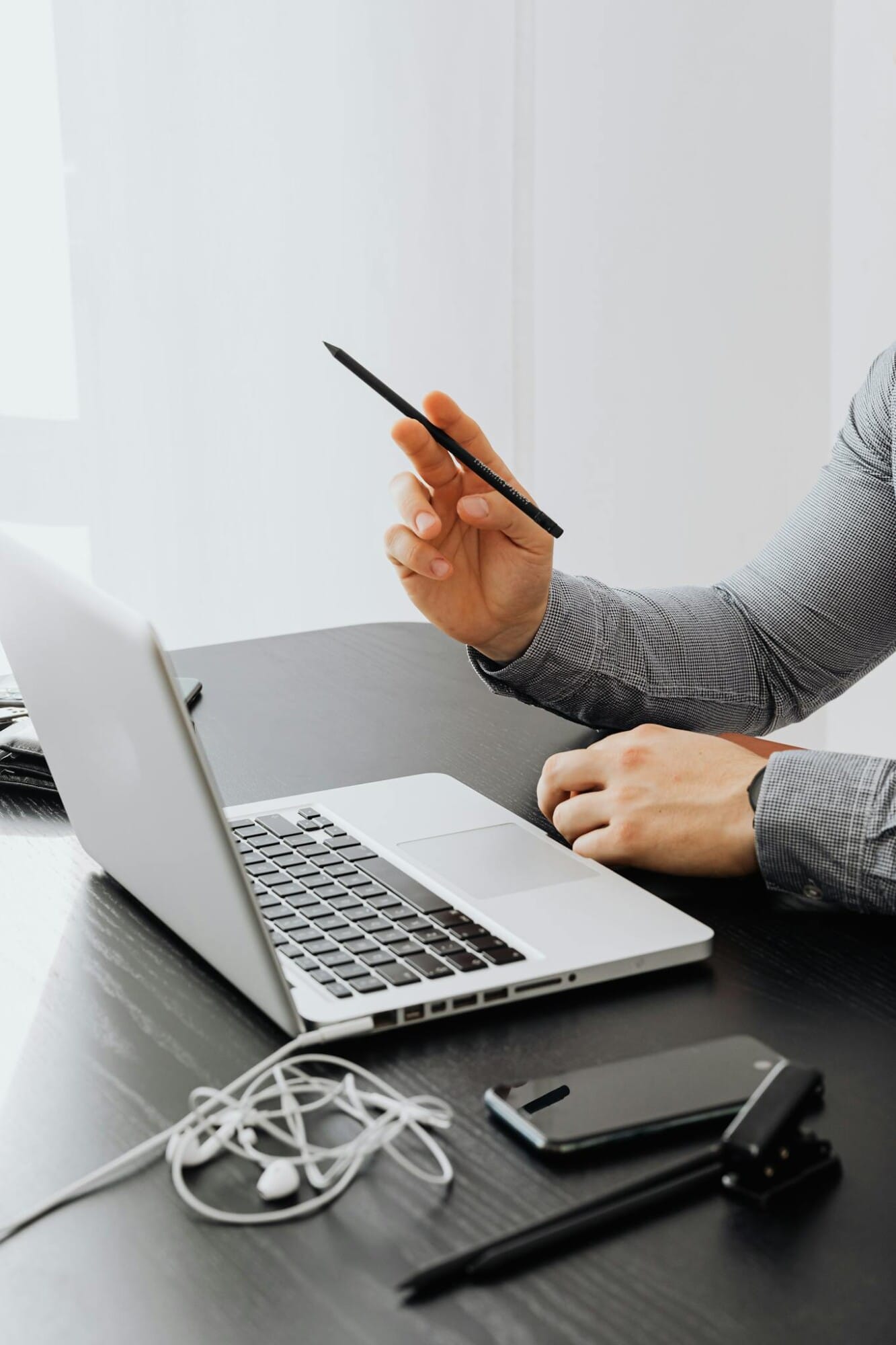 Services 3 Close-up of a person using a laptop in a modern office setting with electronic devices on the table.